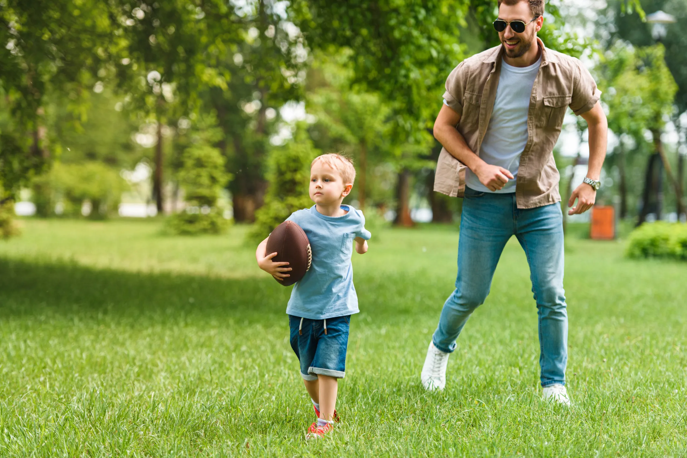 Young child playing football with parent